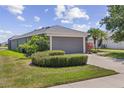Exterior view of a well maintained single-story home with gray garage door and colorful, manicured landscaping at 9840 50Th Street E Cir, Parrish, FL 34219