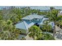 Beautiful two-story home featuring a well-manicured lawn and mature tropical landscaping with lush palm trees at 1042 N Casey Key Rd, Osprey, FL 34229
