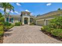 Elegant exterior with a paver driveway leading to an attached garage, complemented by a well-maintained lawn at 12311 Newcastle Pl, Lakewood Ranch, FL 34202