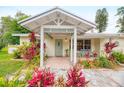 Inviting front entrance with covered porch, pastel door, brick walkway, and mature tropical landscaping at 1731 Redwood St, Sarasota, FL 34231