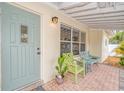 Close-up of front porch featuring pastel-colored chairs, brick tile, and a charming blue front door at 1731 Redwood St, Sarasota, FL 34231