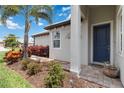 Inviting entryway with a blue front door, column, and lush landscaping at 17885 Cherished Loop, Bradenton, FL 34211