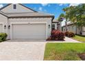 Garage and landscaped front yard of a charming single-story house with a paver driveway at 17885 Cherished Loop, Bradenton, FL 34211