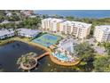 Aerial view of condos featuring a pool, tennis courts, scenic pond, and beautiful landscaping at 242 Hidden Bay Dr # 603, Osprey, FL 34229