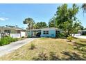 Charming single-story home with a light blue exterior, carport, mature trees and landscaping at 305 Palmetto W Rd, Nokomis, FL 34275