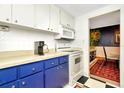 Bright kitchen with white appliances, blue cabinets, and decorative red rug at 36750 Us 19 N # 03102, Palm Harbor, FL 34684