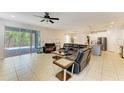 Open-concept living room with tile flooring, ceiling fan and sliding glass doors to a screened lanai at 6125 35Th E Ct, Bradenton, FL 34203