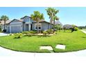 Beautiful gray house featuring lush green lawns, swaying palm trees, and a terra cotta tiled roof at 6800 Dunlin Ct, Sarasota, FL 34241