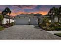 Charming home featuring a three-car garage, a paved driveway, and lush landscaping illuminated by a striking sunset sky at 11713 Goldenrod Ave, Bradenton, FL 34212