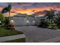A charming home with a paved driveway leading to a three-car garage, enhanced by lush landscaping and a sunset backdrop at 11713 Goldenrod Ave, Bradenton, FL 34212