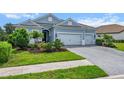 Light blue home with a three-car garage and a beautifully landscaped front yard at 13319 Deep Blue Pl, Bradenton, FL 34211