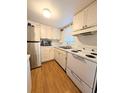 Galley kitchen with stainless steel refrigerator and white appliances and cabinetry at 1819 Restful Dr # N25, Bradenton, FL 34207