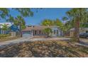 Charming single-story home featuring a blue exterior, well-maintained lawn, and mature palm trees at 1931 Bahia Vista St, Sarasota, FL 34239