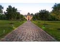 Stunning estate home with a long brick driveway lined with manicured trees and illuminated landscape lighting at 20706 79Th E Ave, Bradenton, FL 34202