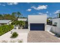 Modern home with a blue garage door, light-colored facade, front courtyard, and a brick driveway at 2365 Novus St, Sarasota, FL 34237