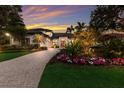 A home with a paved driveway, well-maintained landscaping, colorful flowers, and exterior lighting at 3302 Sabal Cove Ln, Longboat Key, FL 34228