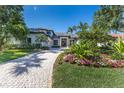 Beautifully landscaped front yard with a winding paver driveway and lush tropical plants at 3302 Sabal Cove Ln, Longboat Key, FL 34228