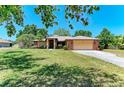 Charming single-story home featuring a well-manicured lawn, mature trees, and an attached two-car garage at 410 136Th E Ct, Bradenton, FL 34212