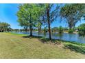 Scenic waterfront view featuring a lush green lawn and a tranquil pond bordered by mature trees at 410 136Th E Ct, Bradenton, FL 34212