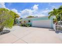 Inviting home exterior with a large driveway, tropical landscaping and garage at 410 Garfield Dr, Sarasota, FL 34236