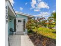 Inviting entrance with tile walkway, red flowering tree, and a charming covered front porch and blue exterior siding at 4309 Pinfish Ln, Palmetto, FL 34221