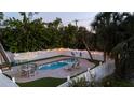An aerial view of the fenced-in pool area with lounge chairs, dining table, artificial grass, and pavers at 501 Key Royale Dr, Holmes Beach, FL 34217