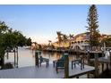 A dock view of waterfront homes with boat docks, palm trees, and outdoor seating at 501 Key Royale Dr, Holmes Beach, FL 34217