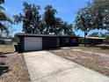Charming single-story home showcasing a dark gray exterior, a two-car garage and mature trees in the front yard at 5030 Lahaina Dr, Sarasota, FL 34232