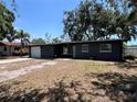 Charming single-story home showcasing a dark gray exterior, a two-car garage and mature trees in the front yard at 5030 Lahaina Dr, Sarasota, FL 34232