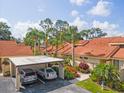 Exterior view of home with carport, red tile roof, mature landscaping and neighborhood features at 5336 Huntingwood Ct # 24, Sarasota, FL 34235