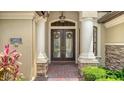 Charming double front doors with glass inserts and decorative wreaths, flanked by elegant columns and brick accents at 6931 Brier Creek Ct, Lakewood Ranch, FL 34202