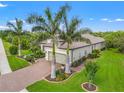 A lovely home with a two-car garage, brick driveway, lush lawn and landscaping, and a tile roof at 9774 Highland Park Pl, Palmetto, FL 34221