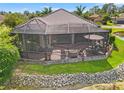 A relaxing screened-in porch with a tile patio, fire pit, and comfortable outdoor furniture overlooking a pond at 9774 Highland Park Pl, Palmetto, FL 34221