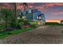 Beautiful waterfront home with a blue exterior, mature landscaping, and a paver driveway at 12 Tidy Island Blvd, Bradenton, FL 34210