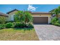 Charming single-Gathering home with a red-tiled roof, two-car garage, paver driveway, and tropical landscaping at 12315 Canavese Ln, Venice, FL 34293