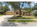 Traditional yellow home with lush landscaping, a red front door, mature trees, and a two-car garage at 127 Mill E Run, Bradenton, FL 34212