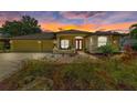Charming yellow home with a red front door, well-manicured lawn during sunset with two-car garage at 127 Mill E Run, Bradenton, FL 34212