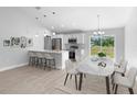 Open-concept kitchen and dining area with white cabinets, breakfast bar, and stainless steel appliances at 343 Tenk St, Port Charlotte, FL 33953