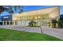 Modern home with a wall of windows, a spacious driveway, and lush green lawn at 4123 Bay Shore Rd, Sarasota, FL 34234