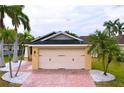 Charming home featuring a two-car garage, brick driveway, and lovely landscaping with decorative stones and palm trees at 4826 San Ortebello Dr, Bradenton, FL 34208