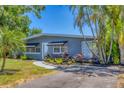 Charming home's entrance featuring black awnings, a welcoming white door, and lush landscaping at 6013 Murdock Ave, Sarasota, FL 34231