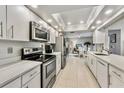 Modern kitchen with white cabinets, stainless steel appliances, quartz countertops, and open to dining area at 7311 7Th W Ave # 7311, Bradenton, FL 34209