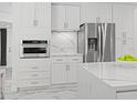 Bright kitchen boasts white cabinetry, stainless steel appliances, and luxurious marble countertops at 172 Sea Anchor Dr, Osprey, FL 34229