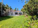 Beautiful backyard with a sparkling pool, lush landscaping, and lovely patio furniture at 173 Bath Club N Blvd, North Redington Beach, FL 33708