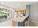 Well-lit kitchen with breakfast bar, bright cabinets, stainless appliances, and sliding glass doors to patio at 2353 Rosewood Ln, North Port, FL 34289