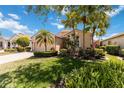 Single Gathering home with lush landscaping, mature palm trees, and brick driveway at 6519 43Rd E Ct, Sarasota, FL 34243