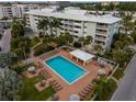 Aerial view showcasing the pool and multi-story condo buildings surrounded by lush landscaping and mature trees at 6610 Midnight Pass Rd # 11, Sarasota, FL 34242