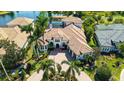 Aerial view of a sprawling estate home surrounded by palm trees, lush landscaping, and a serene lake at 6819 Dominion Ln, Lakewood Ranch, FL 34202