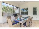 Outdoor dining area with a built-in grill, countertop, cabinets, wicker chairs and a glass table with elegant place settings at 749 Tailwind Pl, Sarasota, FL 34240