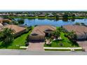 Waterfront home featuring tile roof, attached garage, and manicured lawn with lake views at 8297 Barton Farms Blvd, Sarasota, FL 34240